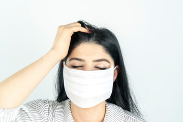 Young woman with surgical mask on face against SARS-CoV-2. COVID-19 Pandemic Coronavirus Young girl in white room wearing face mask