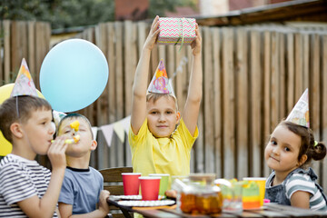 Cute funny nine year old boy celebrating his birthday with family or friends in a backyard....