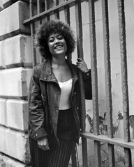 Happy curly woman holding bars in the street and looking at camera.