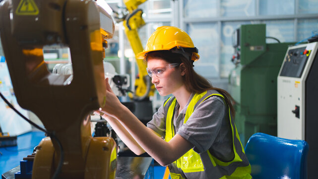 Professional and intelligence female engineer used her technical hard skill to fix, repair or maintenance machine robotic arm in factory or industrial, examining or welding automobile machine workshop