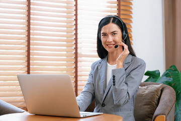 Female call center operator or customer service helpdesk staff working on workspace while talking...