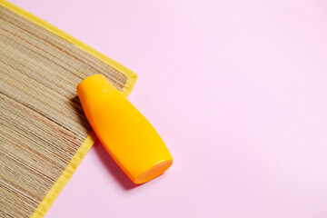 Beach mat and sunscreen on pink background. Beach concept. Feminine concept. Space for text.