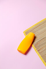 Beach mat and sunscreen on pink background. Beach concept. Feminine concept. Space for text.