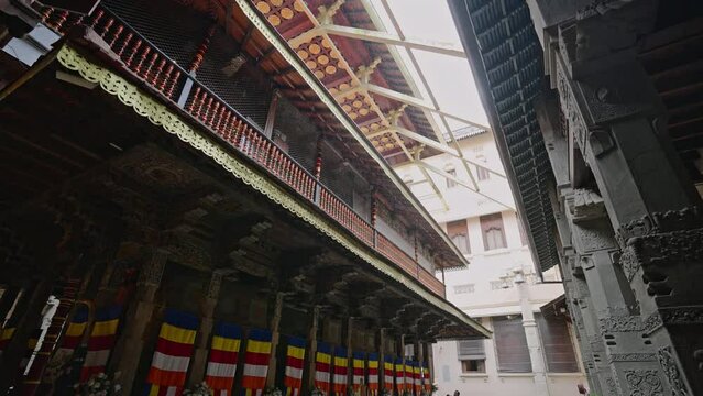 Rain drizzles on ancient Sri Dalada Maligawa, Kandy. Worshipers, tourists shelter under temple ornate eaves. Sacred, tranquil vibes in rain-soaked historic site. Cultural architecture, travel unite.