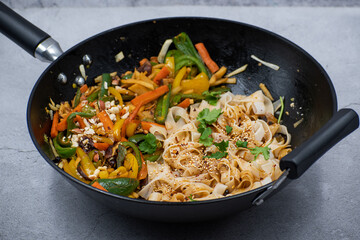 Mixed vegetables and mushroom stir fry in cast iron wok along with white wheat noodles