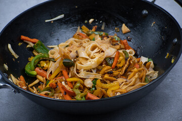 Mixed vegetables and mushroom stir fry in cast iron wok along with white wheat noodles