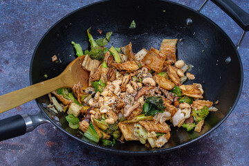 Vegan tofu skins stir fried with broccoli, bok choy. Cast iron wok cooking
