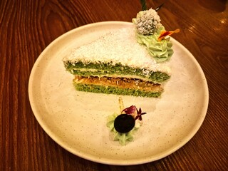 A piece of green cake with coconut flakes on top is filled with brown sugar.
