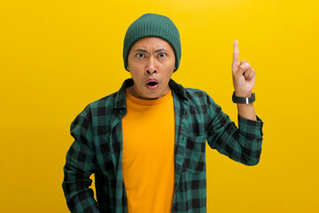 A surprised young Asian man, wearing a beanie hat and casual shirt, is pointing upward in amazement...