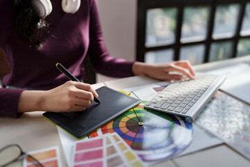 Creative designer woman using laptop to work about graphic design with new project in home studio