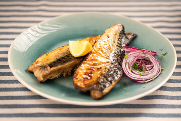 Grilled mackerel fillet on a plate with lemon and blue onion. Mediterranean cuisine