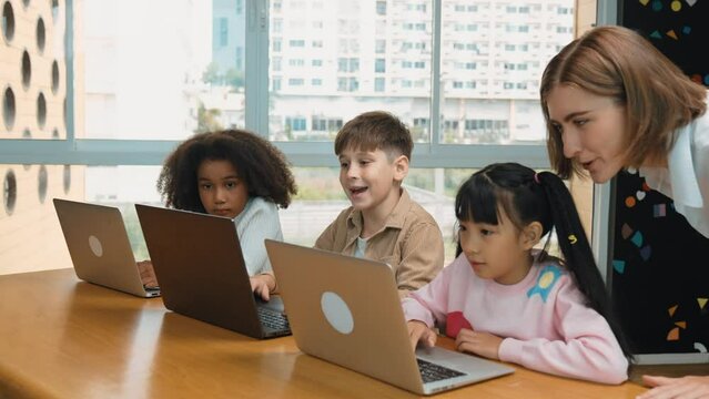 Smart teacher teaching and looking student using laptop at classroom. Professional instructor explained about programing engineering code or prompt while studying and learning program. Erudition.