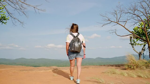 Active senior Asian woman hikes Pidurangala Rock. Mature traveler explores, enjoys serene mountain landscape. Solo hiker with backpack on adventure, embracing eco tourism, wellness in nature. Slowmo