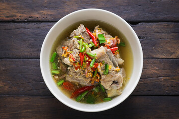 Thai food, Spicy Pork Soup, tom leng, in a white bowl placed on a wooden table is a highly popular spicy food. Popular authentic Thai food concept.