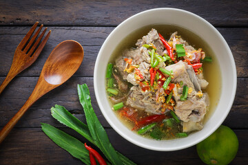 Thai food, Spicy Pork Soup, tom leng, in a white bowl placed on a wooden table is a highly popular spicy food. Popular authentic Thai food concept.