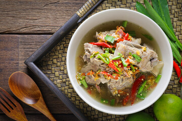 Thai food, Spicy Pork Soup, tom leng, in a white bowl placed on a wooden table is a highly popular spicy food. Popular authentic Thai food concept.