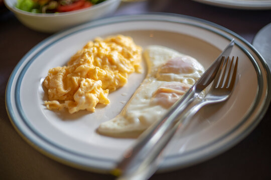 Scrambled eggs and fried egg on the table for breakfast