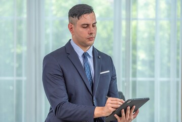 Fototapeta premium A man in a suit is using a tablet.