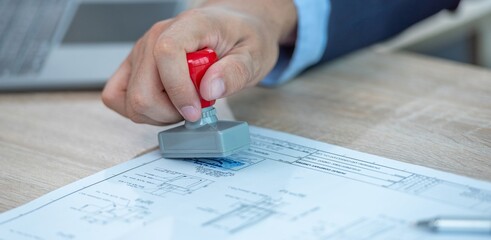 A person stamping a document with a rubber stamp.