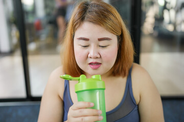 Obese asian woman dieting Weight loss in sportswear drink healthy drink. Sporty asian fat female...