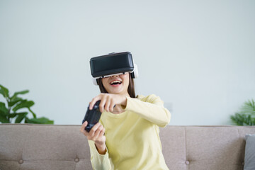 Young Asian woman gamer wearing virtual reality touching air during the VR experience  Future home...