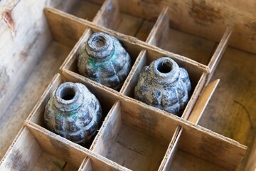  Vintage wartime explosive grenade casings in a wooden box.                              