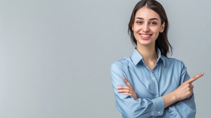 Happy young smiling professional business woman wearing blue shirt looking at camera pointing finger away at copy space showing aside presenting advertising offer standing isolated at gray background 