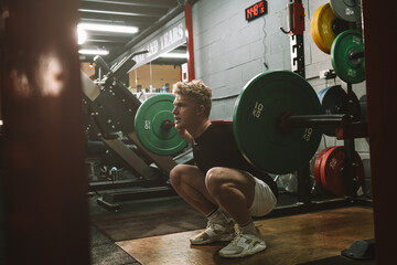 Full length shot of a male crossfit athlete doing barbell squats at the gym