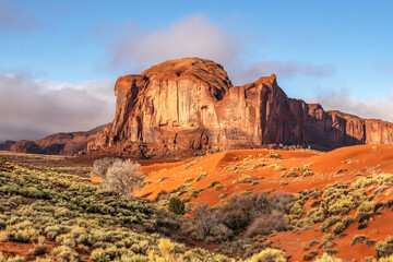 Low early morning light bounces off a mountain formation in Monument Valley, casting a bright...