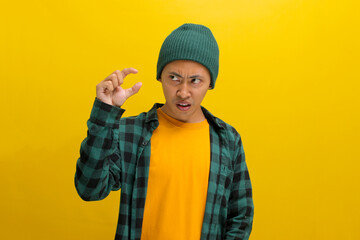 A displeased Asian man, dressed casually in a beanie hat and casual clothes, is gesturing a small...