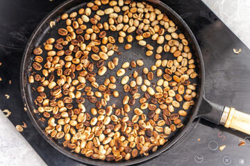 Coffee is roasted in a cast iron pan on an induction hob. Close-up, chosen focus.