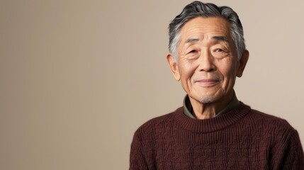 Fototapeta premium portrait of Asian elderly man is 65 years old in deep marsala color sweater on beige color background