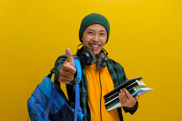 Confident Asian student in beanie and casual clothes, carrying backpack and headphones, Holding a...