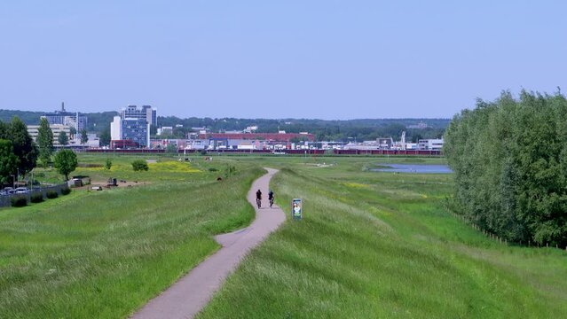 Twee wielrenners rijden op de dijk vlakbij Arnhem in Nederland. Ze geven elkaar een boks met hun hand en slaan af. 