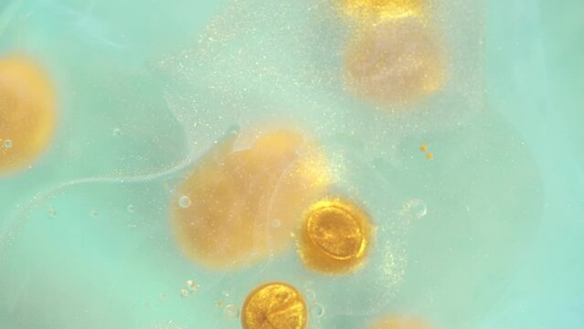 Bright swirls with shiny glittering golden bubbles creating a lively and organic abstract pattern. Color liquid paints moving and mixing. Chaotic motion, bubble flow expansion, curlicue of paints.