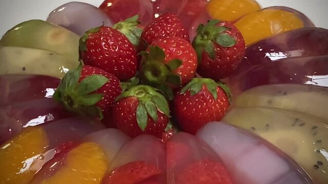 Round shaped fruits pudding. The pudding is made from vanilla jelly, milk, mango juice, filled with fresh strawberry, grape, kiwi, mandarin orange, nata de coco (coconut gel), and strawberry topping.