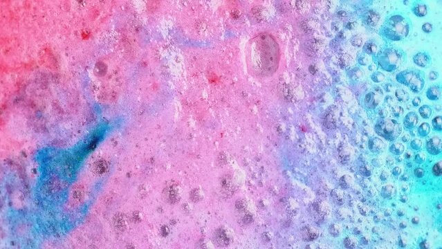 Colorful soapsuds. Pink and blue foam bubbles when dissolving a salt cosmetics bomb, macro. Cosmetics background