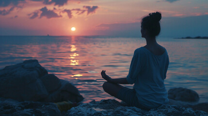 Fototapeta premium Woman meditates by the ocean at sunset, finding peace. 