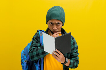 A pensive young Asian student, dressed in a beanie hat and casual shirt, carrying a backpack and holding a notebook, is engrossed in tackling a challenging assignment, deep in thought, exploring ideas