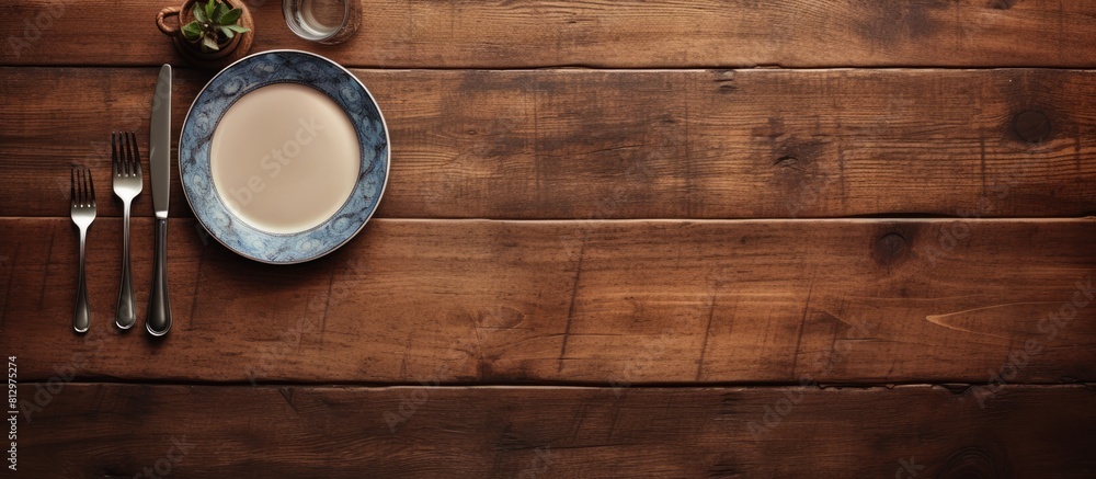 Poster from an aerial perspective a wooden table is adorned with an empty plate and silverware set creating
