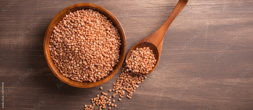 Poster a top view image of buckwheat kernels in a wooden bowl with a spoon set against a white background t