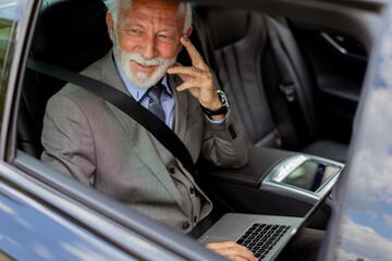 Distinguished gentleman conducting business on the go in his luxurious car