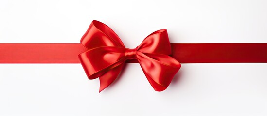 A red satin ribbon bow is seen on a white background in a copy space image
