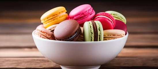 Gordijnen A copy space image of delicious and vibrant French macarons arranged in a bowl on a rustic wooden table © StockKing