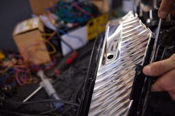 Person fixing Automotive lighting with screwdriver on Motor vehicle headlight