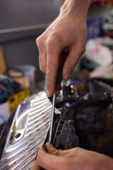 Person fixing Automotive lighting with screwdriver on Motor vehicle headlight