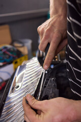 Person fixing Automotive lighting with screwdriver on Motor vehicle headlight