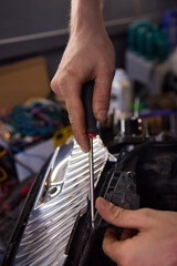 Person fixing Automotive lighting with screwdriver on Motor vehicle headlight