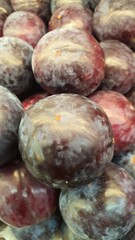 Close up pile of tasty fresh plums sold at the market as a background.