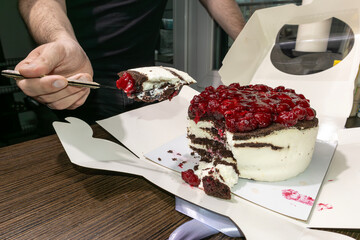 A man eats a cake with a cherry with a spoon. Overeating problem. Social food problem